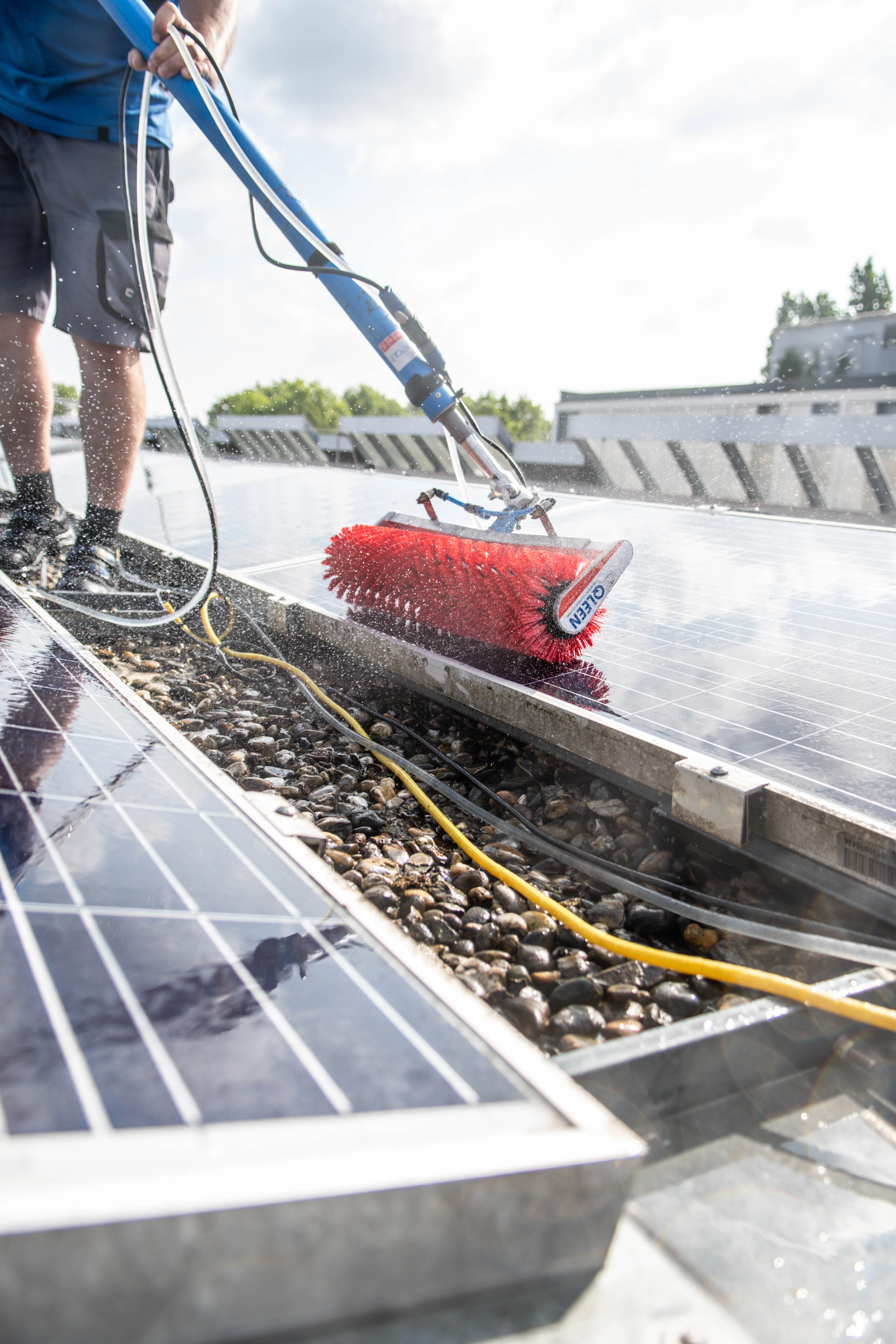 Das Bild zeigt einen Mitarbeiter der Firma Albo-Service, der mit einer Rollenbürste ein Solarpanel reinigt.